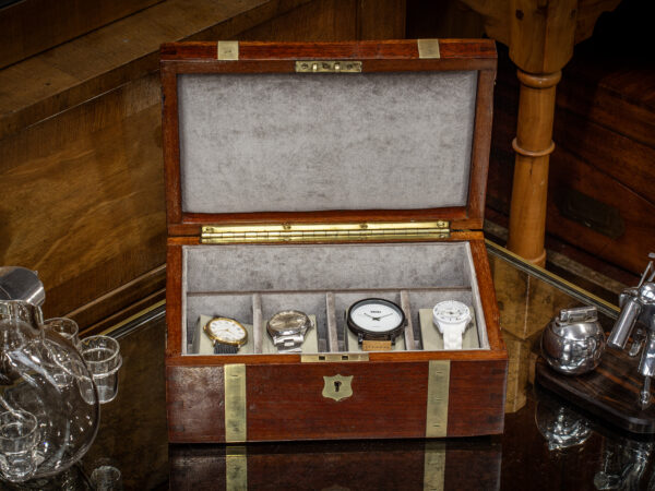 Overview of the Antique Brass Bound Jewellery Box in a decorative collectors setting with watches fitted