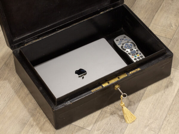 Close up of the Black Leather Dispatch Box in a decorative collectors setting with a laptop and tv remote inside