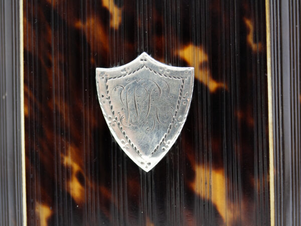 Close up of the silver shield monogram on the back of the Pressed Tortoiseshell Tent Top Tea Caddy